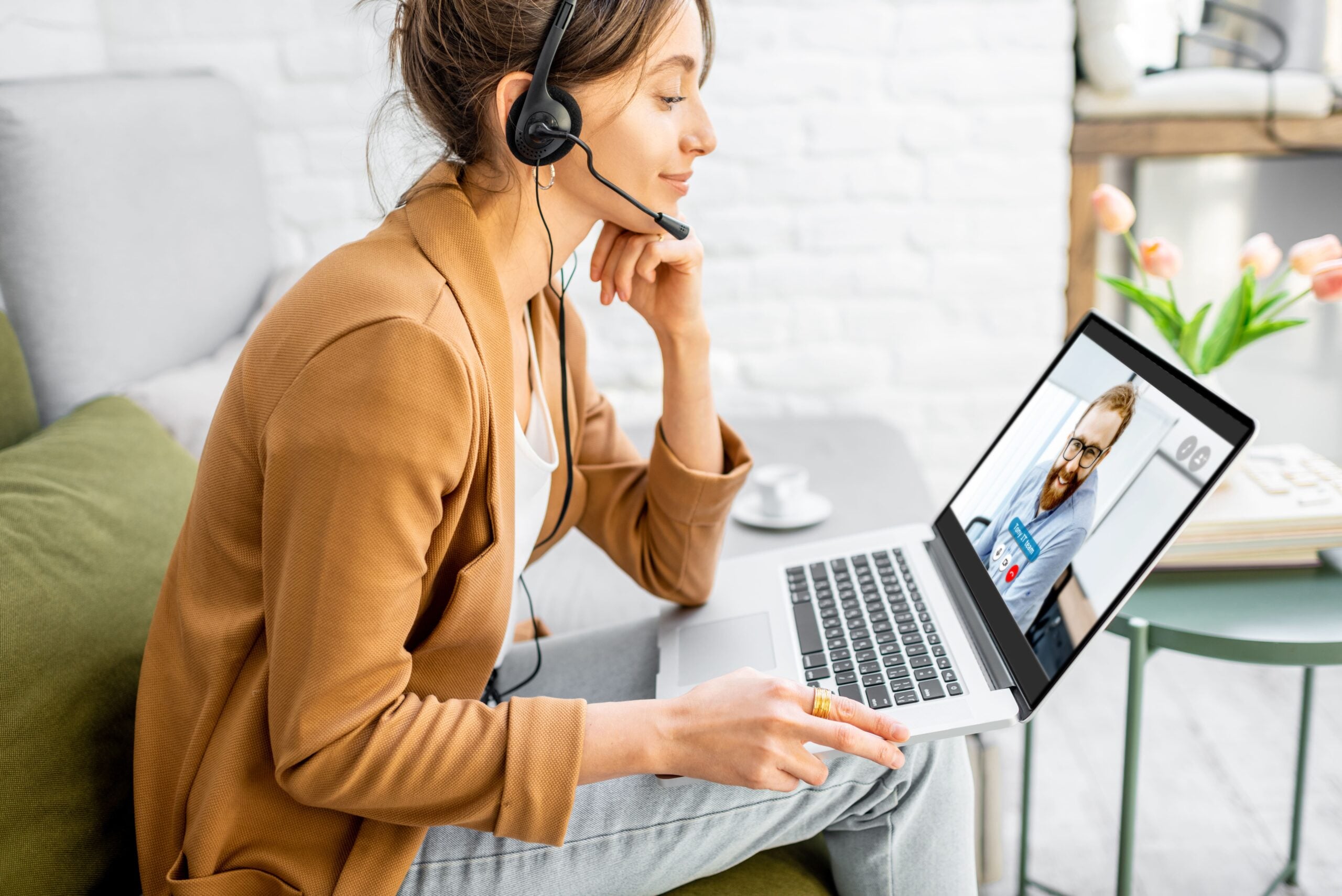 A women conducting an remote interpretation session with her headphones and laptop on her lap.