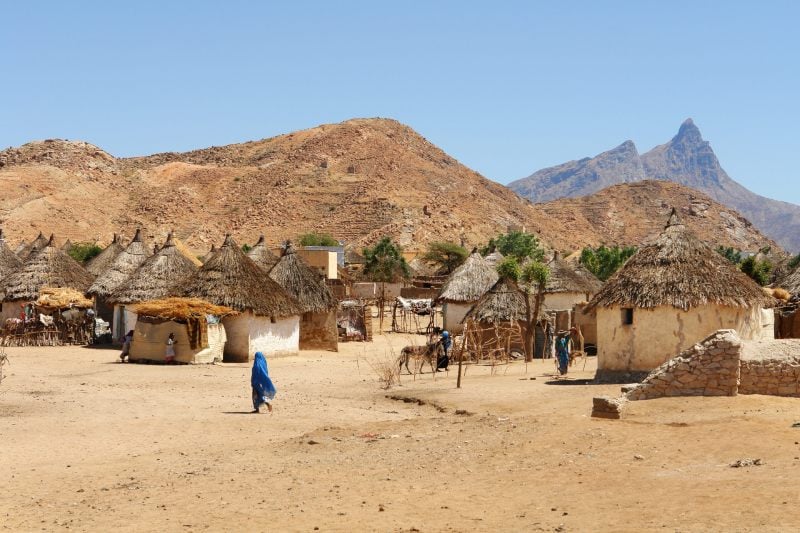 Kunama translation services supporting communication in a rural Kunama-speaking community with traditional homes and mountainous landscape.
